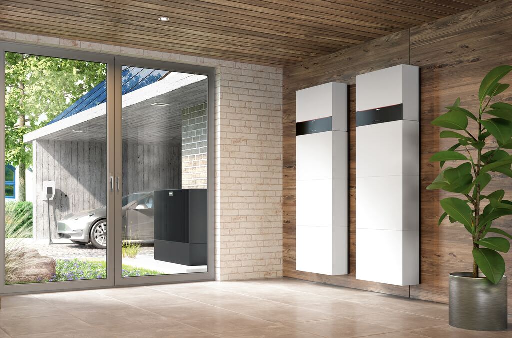 Zwei Viessmann-Stromspeicher Vitocharge VX3 an der Wand, durch die Glastür Wärmepumpe und Ladestation im Carport